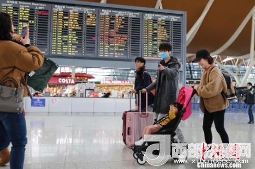 旅客帶著孩子前往辦票柜臺辦理登機(jī)手續(xù)。　殷立勤 攝