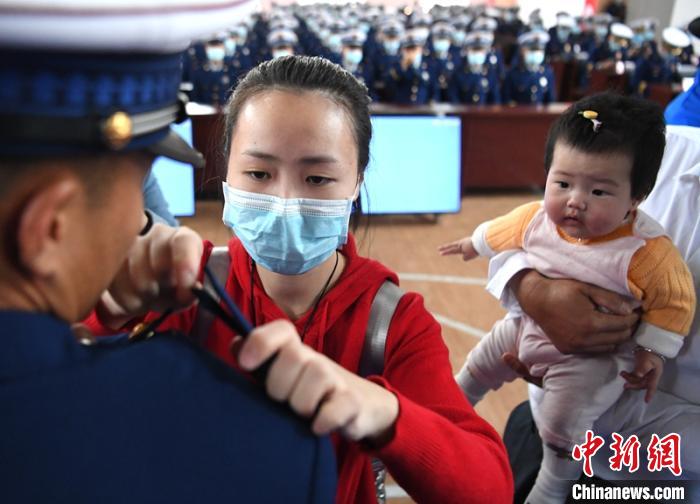 新消防員楊振的妻子彭莉與女兒現(xiàn)場見證丈夫加入“火焰藍(lán)”的神圣時刻?！⒅铱?攝