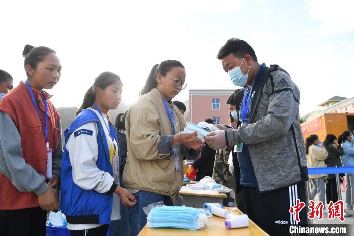 7月7日，考生在拉薩三高考點(diǎn)外領(lǐng)取口罩。　何蓬磊 攝